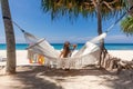 Back View of Travel Woman Sitting on White Hammock on Sandy Beach Royalty Free Stock Photo