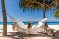 Back View of Travel Woman Sitting on White Hammock on Sandy Beach Royalty Free Stock Photo