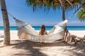 Back View of Travel Woman Sitting on White Hammock on Sandy Beach Royalty Free Stock Photo