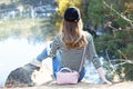 Back view on traveler hipster girl wearing black blazer. Young brave woman sittingon the edge of a cliff alone among trees in