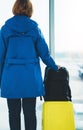 Back view traveler tourist with yellow suitcase backpack is standing at airport on background large window Royalty Free Stock Photo