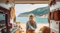 Back view of traveling female artisan standing near truck with handmade accessories on background of sea and mountains. Generative