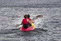 Back view of two athletic women kayaking on the wavy sea