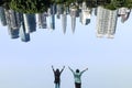 Back view of two people with hands up standing in front of upside down cityscape Kuala Lumpur