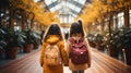 Back view of two schoolgirls with backpacks walking in the greenhouse. Generative AI