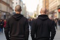 Back view of two skinhead neo-nazis with shaved heads and black sweatshirts in street