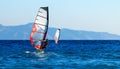 Back view of two windsurfers in action mooving parallel to each other