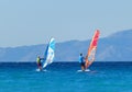 Back view of two windsurfers in action mooving parallel to each other