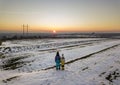 Back view of two young children in warm clothing standing in frozen snow field holding hands on copy space background of setting Royalty Free Stock Photo