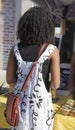 Back view of unrecognizable African American girl in a cute dress with purse standing at a honey vendors stall at a farmers market