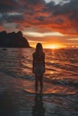 Back View of Unrecognizable Female Silhouette Standing in Rippling Sea Water Enjoying Sunset Over Mountains Royalty Free Stock Photo