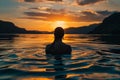 Back View of Unrecognizable Female Silhouette Standing in Rippling Sea Water Enjoying Sunset Over Mountains Royalty Free Stock Photo