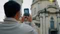 Back view unrecognizable man tourist travels in Europe photographing landmark using camera of mobile phone male blogger Royalty Free Stock Photo