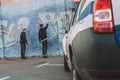 back view of vandals painting graffiti on wall police car