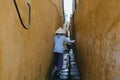 back view of vietnamese woman in traditional hat carrying bicycle on narrow street in Hoi An, Vietnam