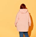 Back view of a voluptuous lady in jeans and bright yellow hoodie putting capuche on her head. Royalty Free Stock Photo