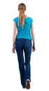 Back view of walking woman in jeans and shirt. Royalty Free Stock Photo