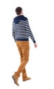 Back view of walking handsome man in jeans and striped sweater.