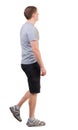 Back view of walking handsome man in shorts and sneakers.