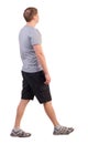 Back view of walking handsome man in shorts and sneakers