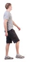 Back view of walking handsome man in shorts and sneakers