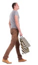 Back view of walking man in gray shirt with shopping bags. Royalty Free Stock Photo