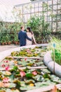 The back view of the walking newlywed couple in the botanic garden. The view of the fountain with water lilies. Royalty Free Stock Photo