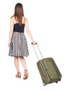 Back view of walking woman with green suitcase.