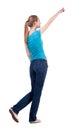 Back view of walking woman in jeans and shirt pointing Royalty Free Stock Photo