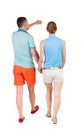 Back view of walking young couple (man and woman) pointing. Royalty Free Stock Photo