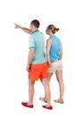 Back view of walking young couple (man and woman) pointing. Royalty Free Stock Photo