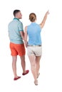 Back view of walking young couple (man and woman) pointing. Royalty Free Stock Photo