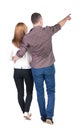 Back view of walking young couple (man and woman) pointing. Royalty Free Stock Photo