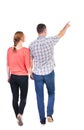 Back view of walking young couple (man and woman) pointing. Royalty Free Stock Photo