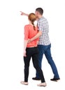 Back view of walking young couple (man and woman) pointing. Royalty Free Stock Photo