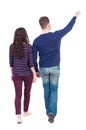 Back view of walking young couple (man and woman) pointing. Royalty Free Stock Photo