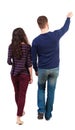 Back view of walking young couple man and woman pointing. Royalty Free Stock Photo