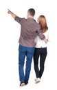 Back view of walking young couple man and woman pointing. Royalty Free Stock Photo