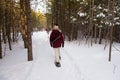 Back view of warmly dressed woman walking with snow shoes in path with couple in soft focus background