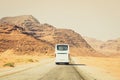 Back view white coach bus drive on asphalt road in scenic Wadi rum mountains in Jordan outdoors take tourist to destination. Royalty Free Stock Photo