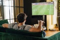 Back view of white man watching football match and drinking beer in front of the TV screen Royalty Free Stock Photo