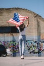 back view of woman with american flag in hands standing on street, 4th july Royalty Free Stock Photo