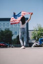 back view of woman with american flag in hands standing on street, 4th july Royalty Free Stock Photo