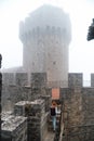 Back view woman with backpack wearing jeans jacket. Fortification, old castle on background. Journey. Vertical photo. Mystical