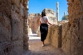 Back view of woman with black short hair looking at ancient ruins with thermal baths, archaeological site in Carthage. Tunisia