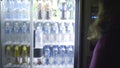 Back view of a woman buying bottled water from automated vending machine. Art. Vending machine with wide variety of soft