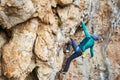 Back view woman climber resting and griping hold, climbs on a rocky wall