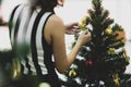 Back view of woman decorating and arranging Christmas tree at home and preparing for winter holidays with calm circumstance