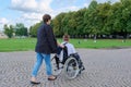 Back view of woman with disabled child in wheelchair in park