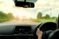 Back view of a woman driving car for summer road trip travel. Car driving with safety on asphalt road. Driver hand holding